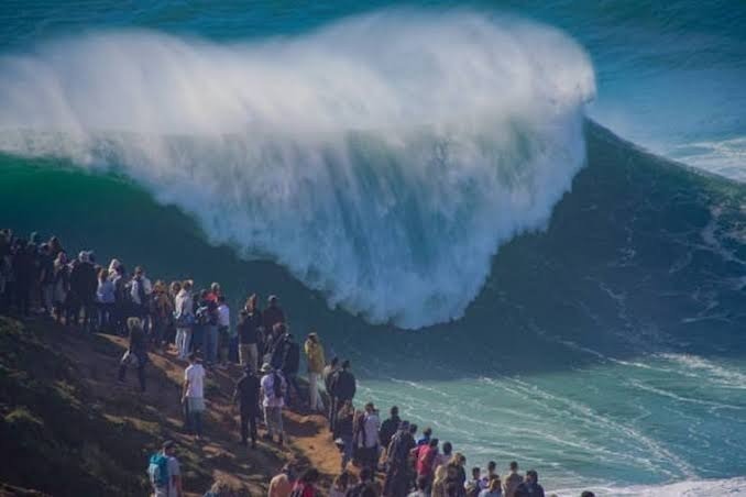 Público frente a una ola gigante en la Praia do Norte, Nazaré